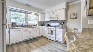 Una cocina moderna con armarios blancos, encimera de granito y horno empotrado.