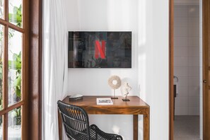 Relax in a stylish room with a large flat-screen TV, comfortable chair, and a spacious desk.