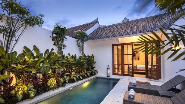 A poolside area with a tiled roof, a lounge chair, and a well-maintained garden with various plants. - Villa Anahera (Seminyak)