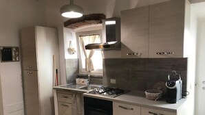 A modern kitchen with a gas stove, sink, and dishwasher. There is a window with curtains and a hanging light fixture. - San Faustino Guesthouse Domus Tuscia (Viterbo)