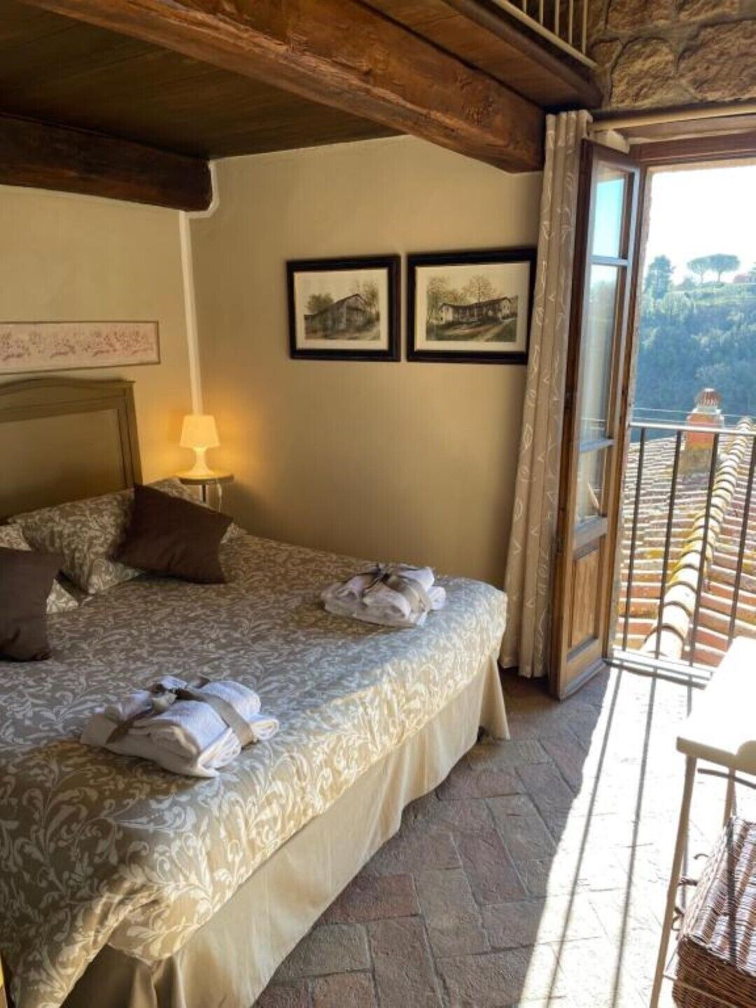 A bedroom with a bed, a nightstand, a lamp, and two framed pictures on the wall.