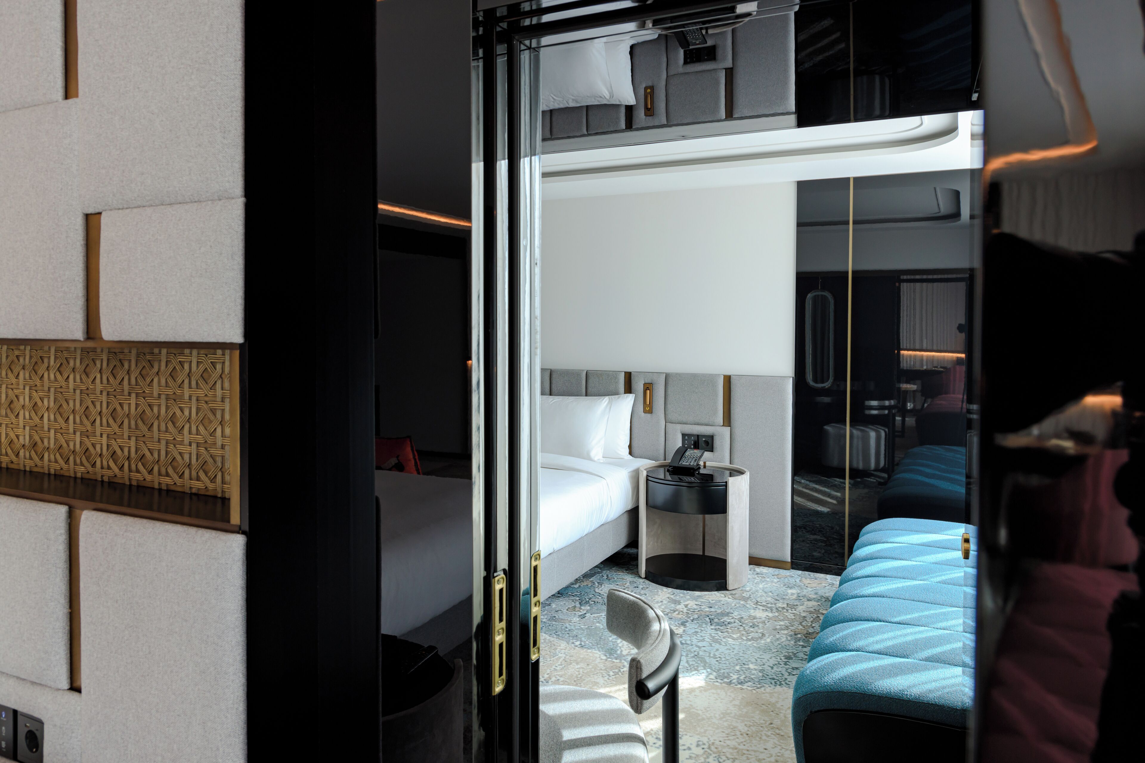 A modern hotel room with a bunk bed, a small bedside table with a lamp, and a large mirror.