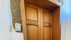 Eine Holztür mit Doppeltür und Fußmatte darunter, ein Lichtschalter sowie ein Thermostat an der Wand.