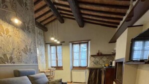 Ein Wohnzimmer mit einer Couch, einem Kamin und einer Küchenzeile mit Fenster.
