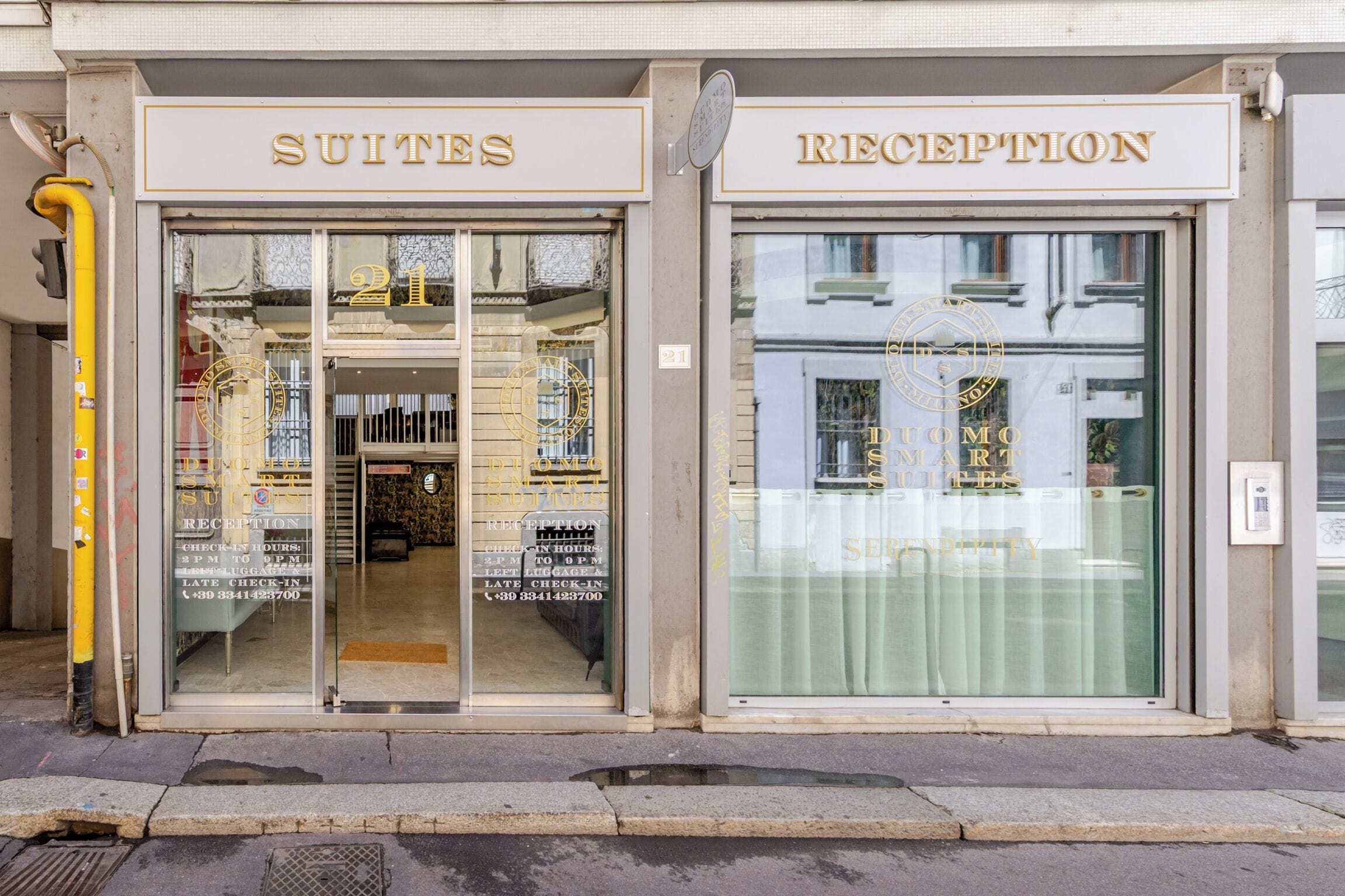 A hotel entrance with 'SUITES' and 'RECEPTION' signs, a check-in counter, and a visible interior with a reception desk.