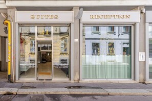 A hotel entrance with 'SUITES' and 'RECEPTION' signs, a check-in counter, and a visible interior with a reception desk. - Duomo Smart Suites (Milan)