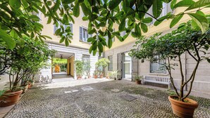 A courtyard with potted plants, a cobblestone floor, and a building entrance. - Duomo Smart Suites (Milan)