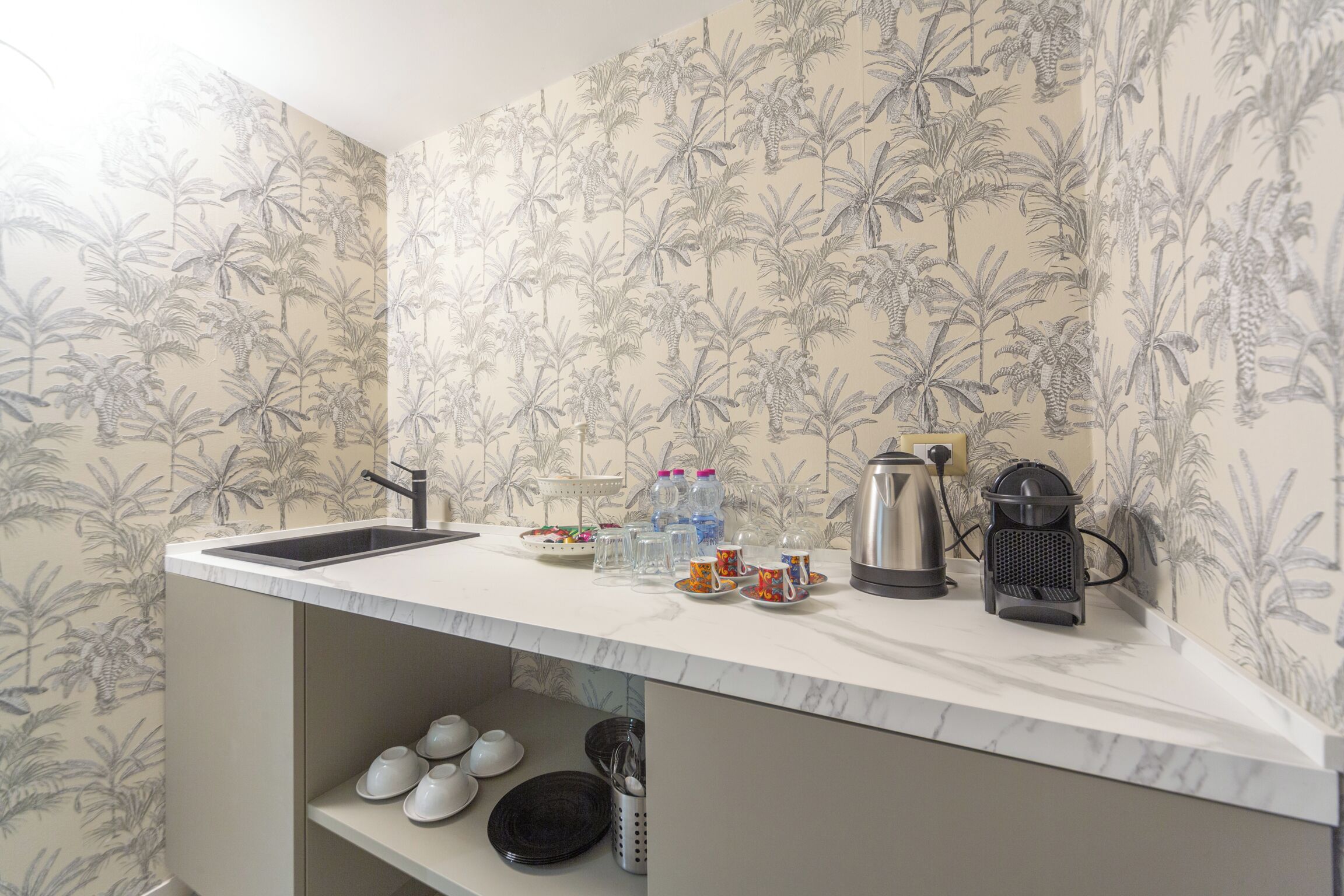 A kitchen with a sink, countertop, and shelves.