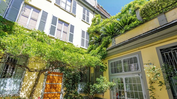 A courtyard with potted plants, a wooden door, and a window with shutters. - Duomo Smart Suites (Milan)