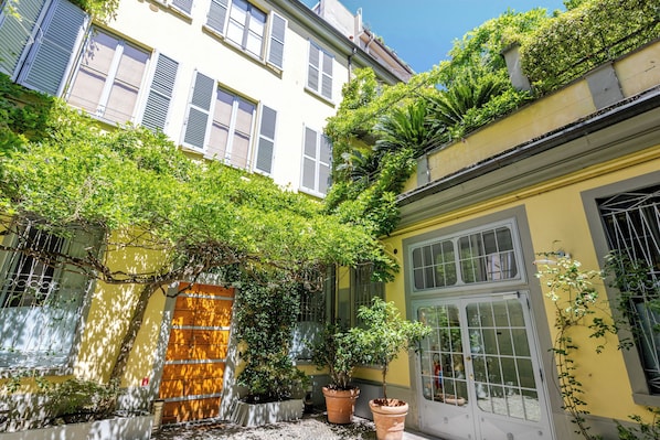 Un patio con plantas en macetas, una puerta de madera y una ventana con contraventanas.