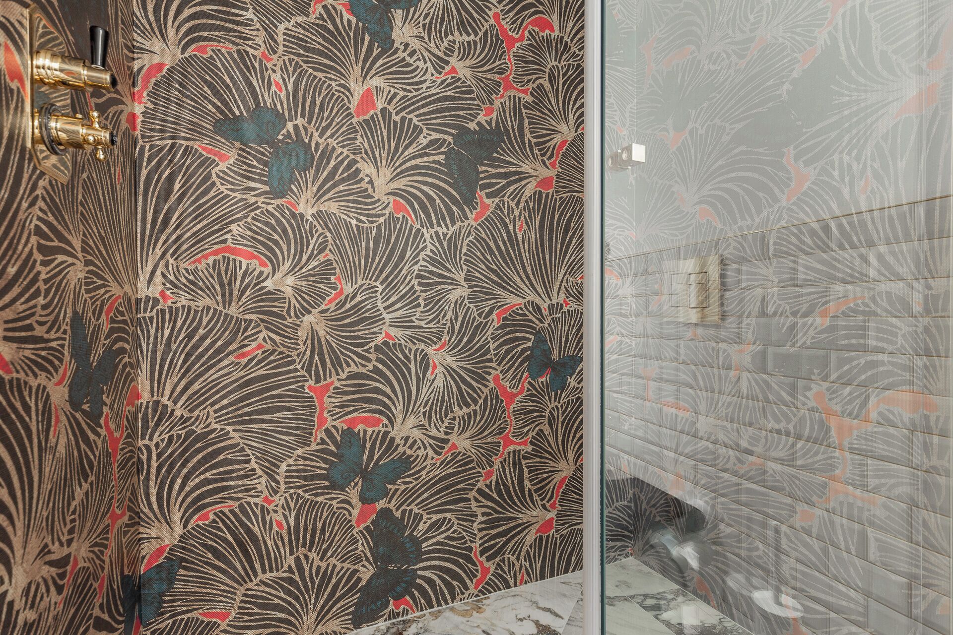 A bathroom with a patterned wallpaper and a tiled shower area.