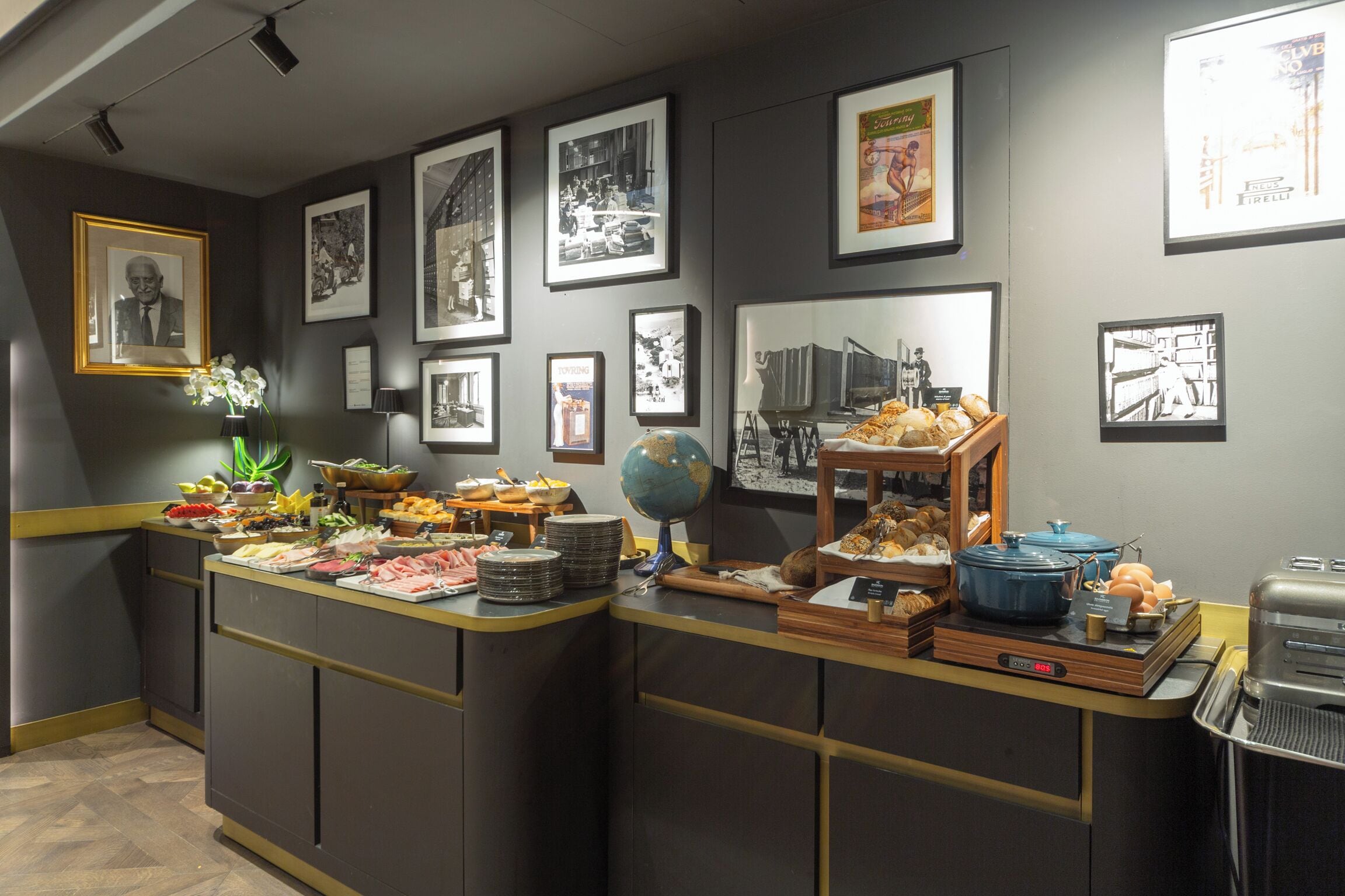 A buffet setup with various food items, a globe, and framed pictures on the wall.
