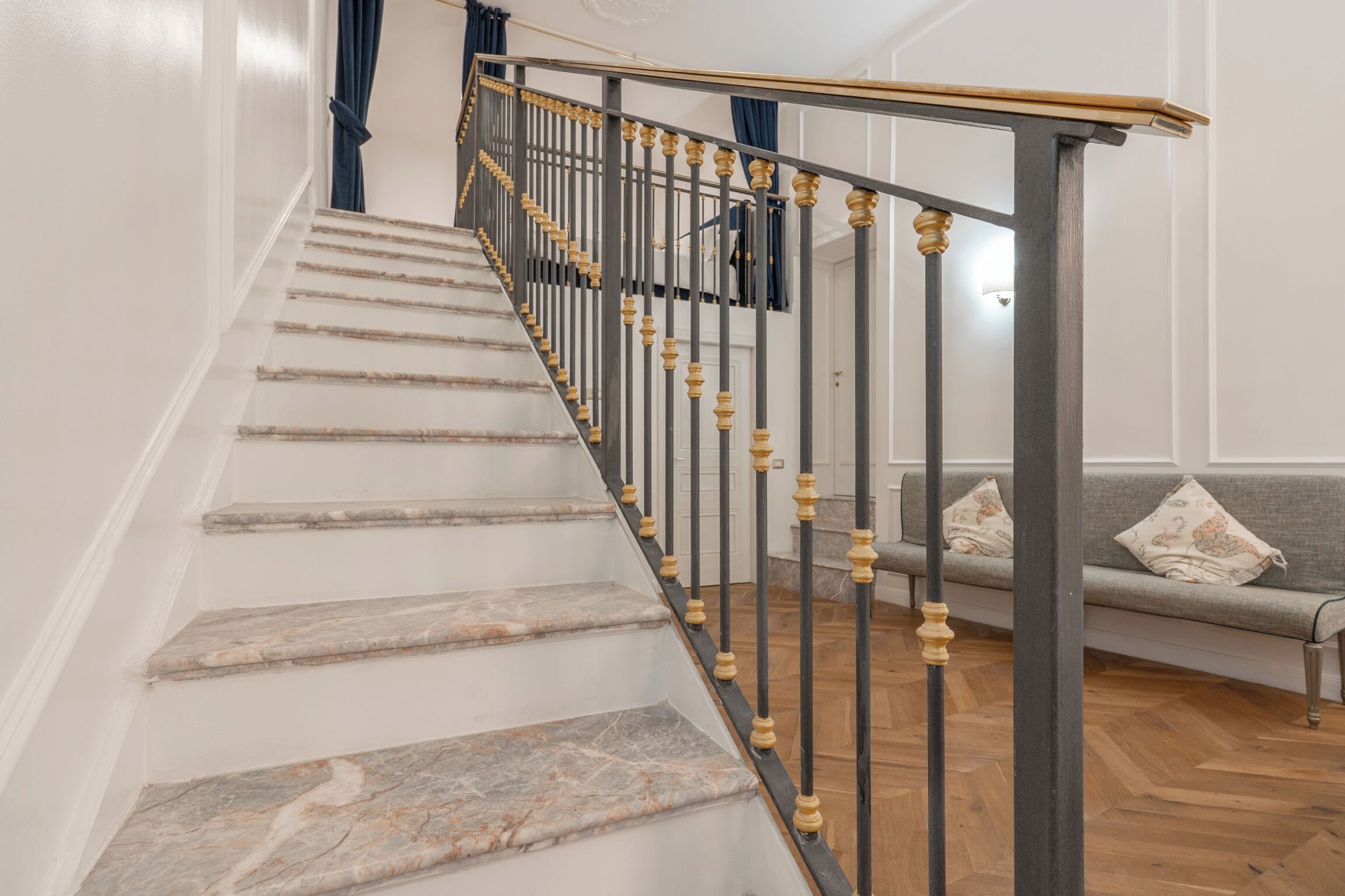 A staircase with marble steps and a metal railing with golden accents.