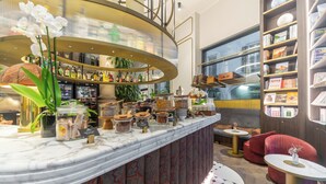 A bar area with a marble countertop, shelves with books and bottles, and a seating area with red sofas and a small table. - Duomo Smart Suites (Milan)