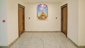 Un pasillo con piso de baldosas, dos puertas de madera y un cuadro con la Torre Eiffel en la pared.