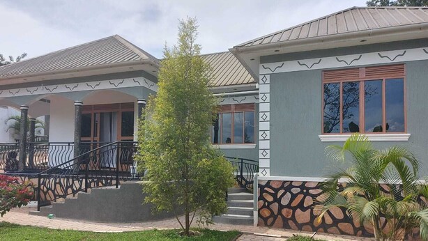 A two-story house with a stone facade, a small porch, and a well-maintained lawn. - Charming House in Matugga, Kampala, Uganda (Matugga)