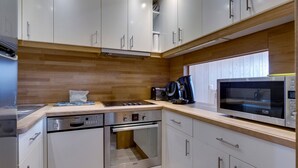 Una cocina moderna con armarios blancos, electrodomésticos de acero inoxidable y un protector contra salpicaduras de madera.