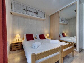 A double bed with a wooden frame, two bedside tables with lamps, and a large mirror.