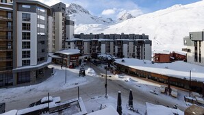 Un hotel moderno con varios pisos, un balneario de esquí al fondo y un paisaje montañoso nevado.