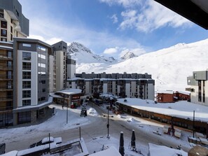 A modern hotel with multiple floors, a ski resort in the background, and a snowy mountain landscape.