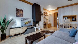 Una sala de estar con sofá, mesa de centro, televisión y chimenea.