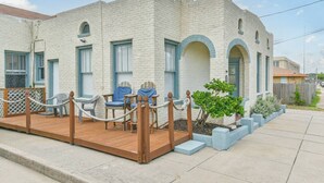 A two-story building with a brick facade, arched windows, and a wooden deck with chairs. - Coastal Blue Cottage is Steps to Beach and Seawall (Galveston)