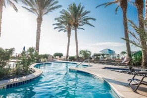 A swimming pool with palm trees and lounge chairs.