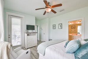 A bedroom with a bed, a ceiling fan, a dresser, and a television.
