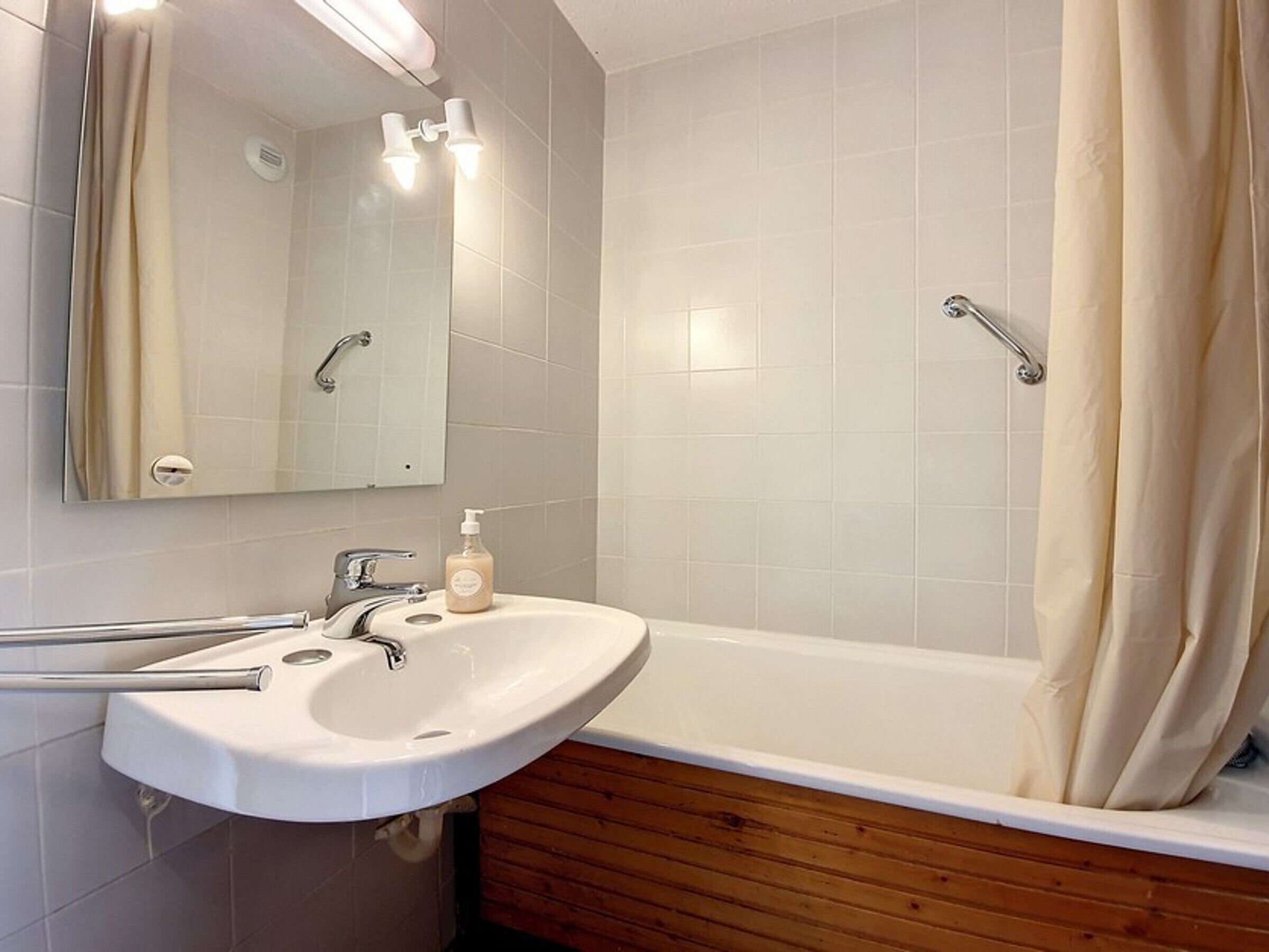 A modern bathroom with a white sink, mirror, and shower.