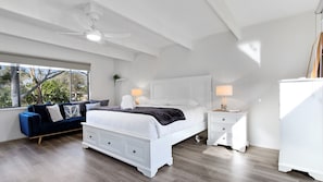Relax in this serene bedroom with a large bed, bedside tables, and a ceiling fan. Enjoy the view from the large window.