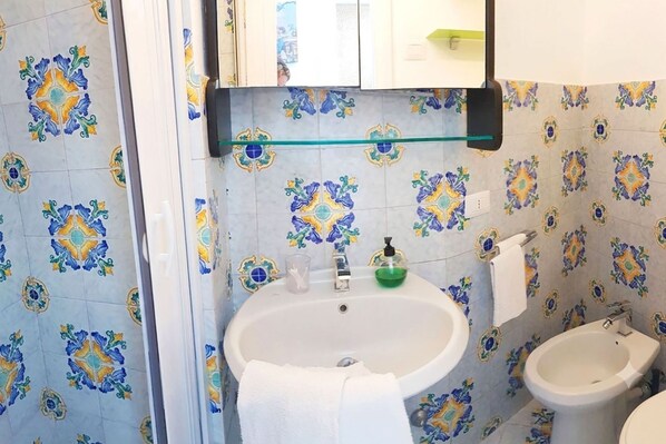 A bathroom with a sink, bidet, and tiled walls.