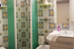A bathroom with a shower, a sink, and a mirror.