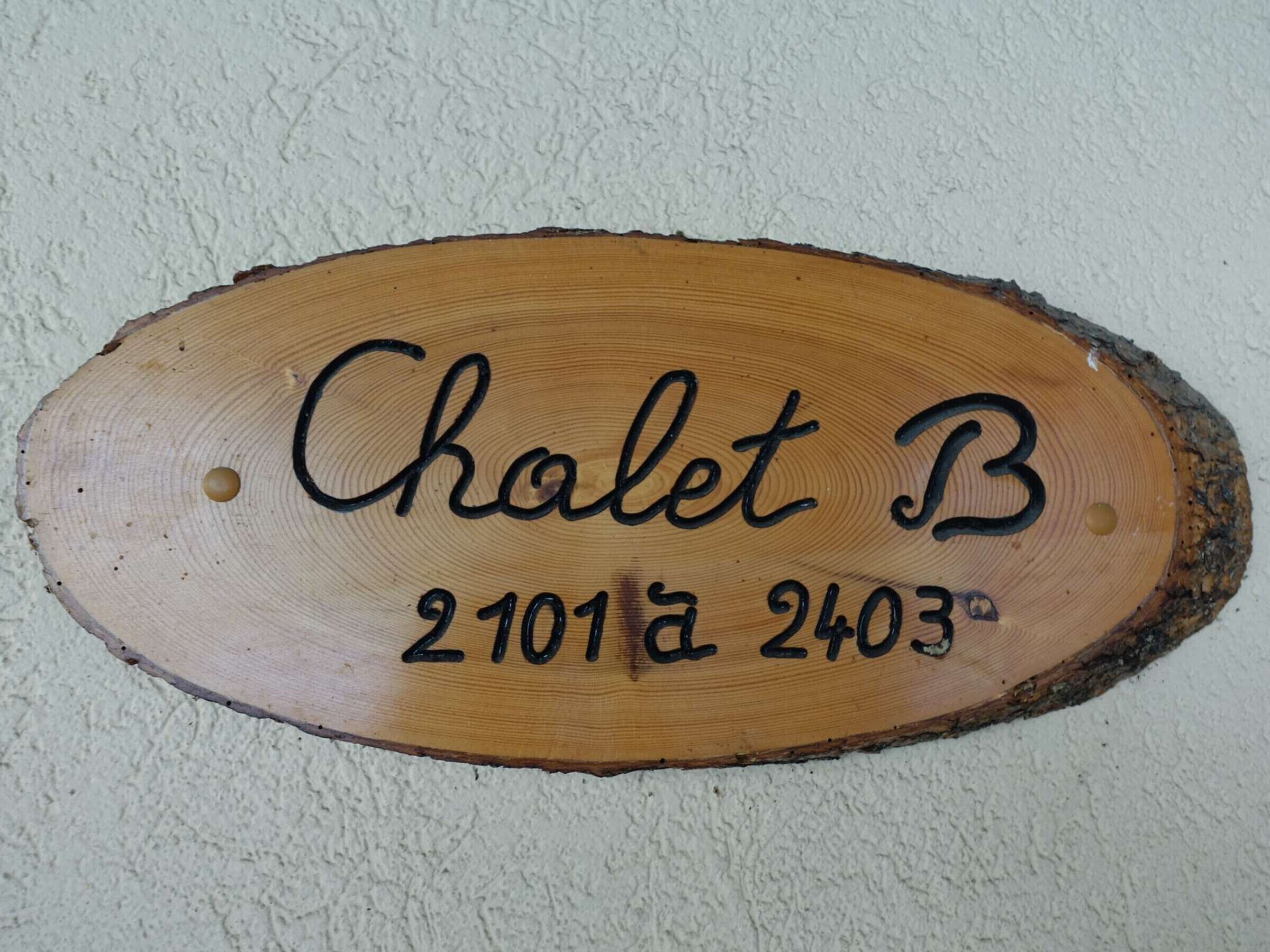 A wooden sign with the text 'Chalet B' and numbers '2101' and '2403' on a textured wall.
