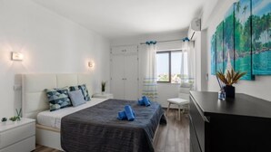 Une chambre moderne avec un lit, des tables de chevet, un bureau et une fenêtre avec des rideaux.