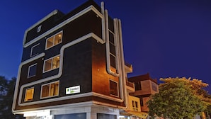Un hôtel moderne à plusieurs étages, doté d’une architecture originale aux lignes angulaires, de grandes fenêtres et d’une enseigne bien visible indiquant « Treebo Trend Stellar Inn ».
