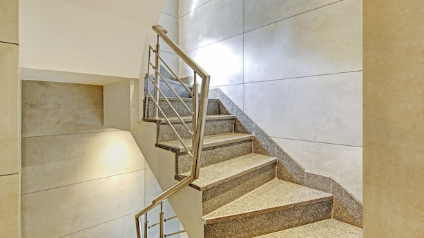 Un escalier moderne avec des marches en granit et des rampes en acier inoxydable.
