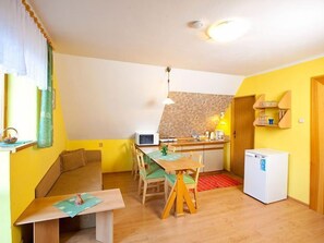 A compact kitchen with a microwave, a small refrigerator, and a dining area with a table and chairs.