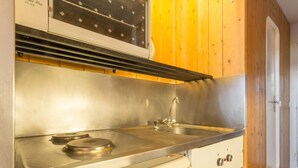 A compact kitchenette with a stainless steel sink, a stove, and a small refrigerator. - Studio 4 pers · Ski-in/Ski-out · Balcony (Les Arcs 1800)