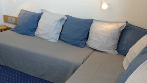 A bed with a grey sheet and blue pillows, a wooden nightstand with a lamp, and a wall-mounted light fixture. - Studio 4 pers · Ski-in/Ski-out · Balcony (Les Arcs 1800)