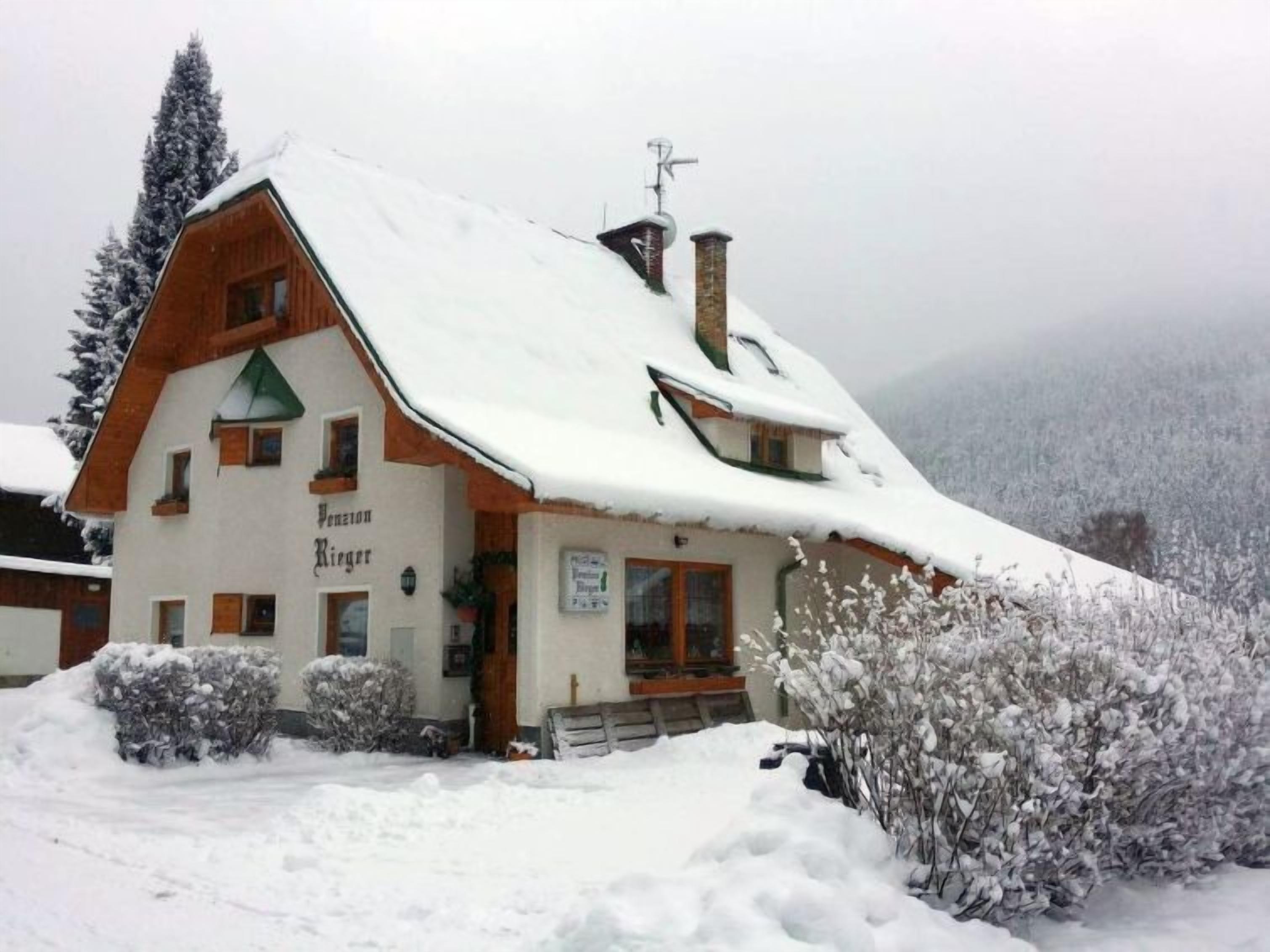 Ein schneebedecktes Holzgebäude mit einem Schild, auf dem "Venezio Rieger" steht.