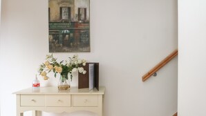 Un bureau blanc orné d’un vase de fleurs, d’une bouteille et d’un livre.
