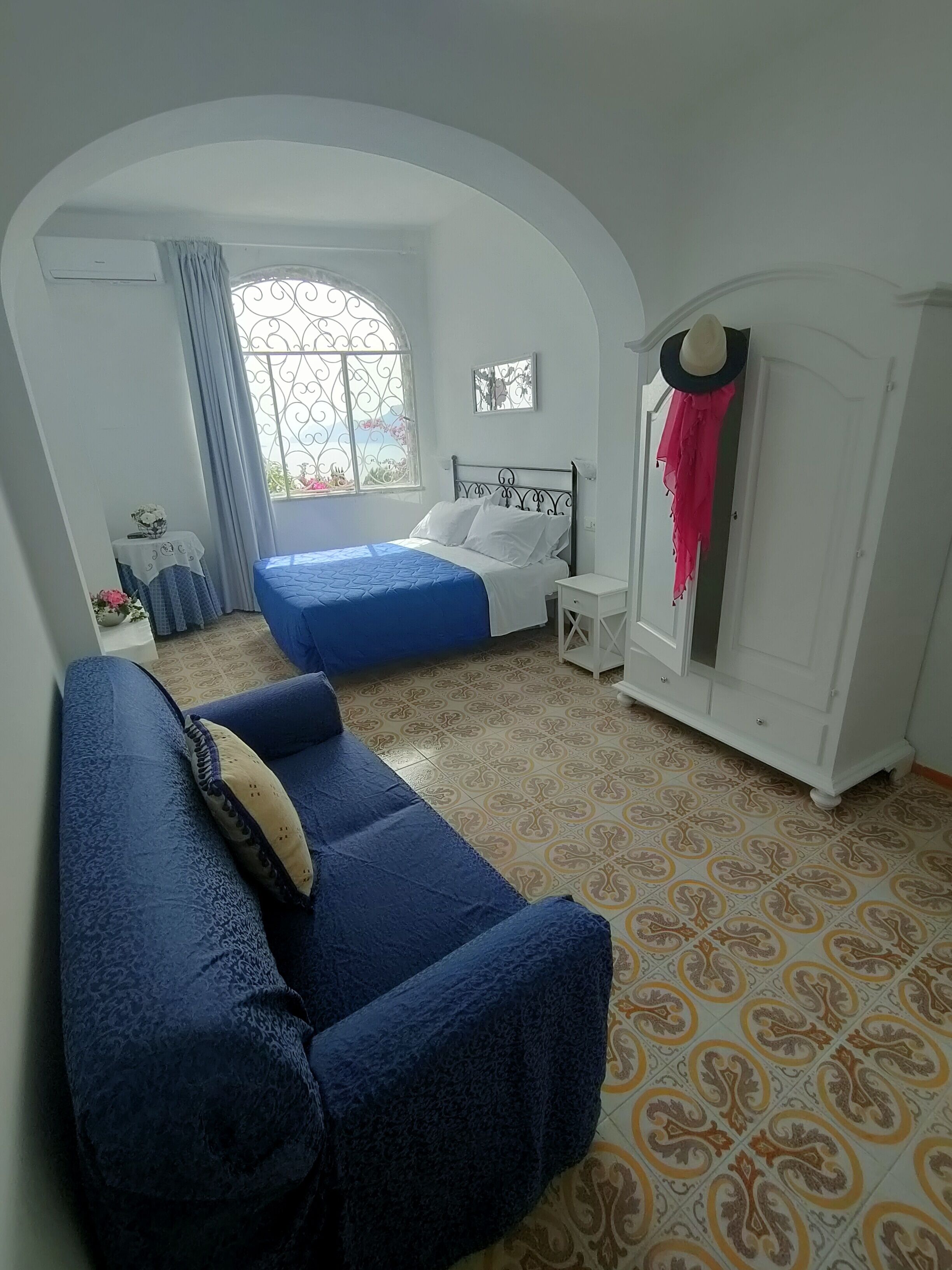 Una camera da letto con un letto, un divano blu, un armadio e una finestra con tende.