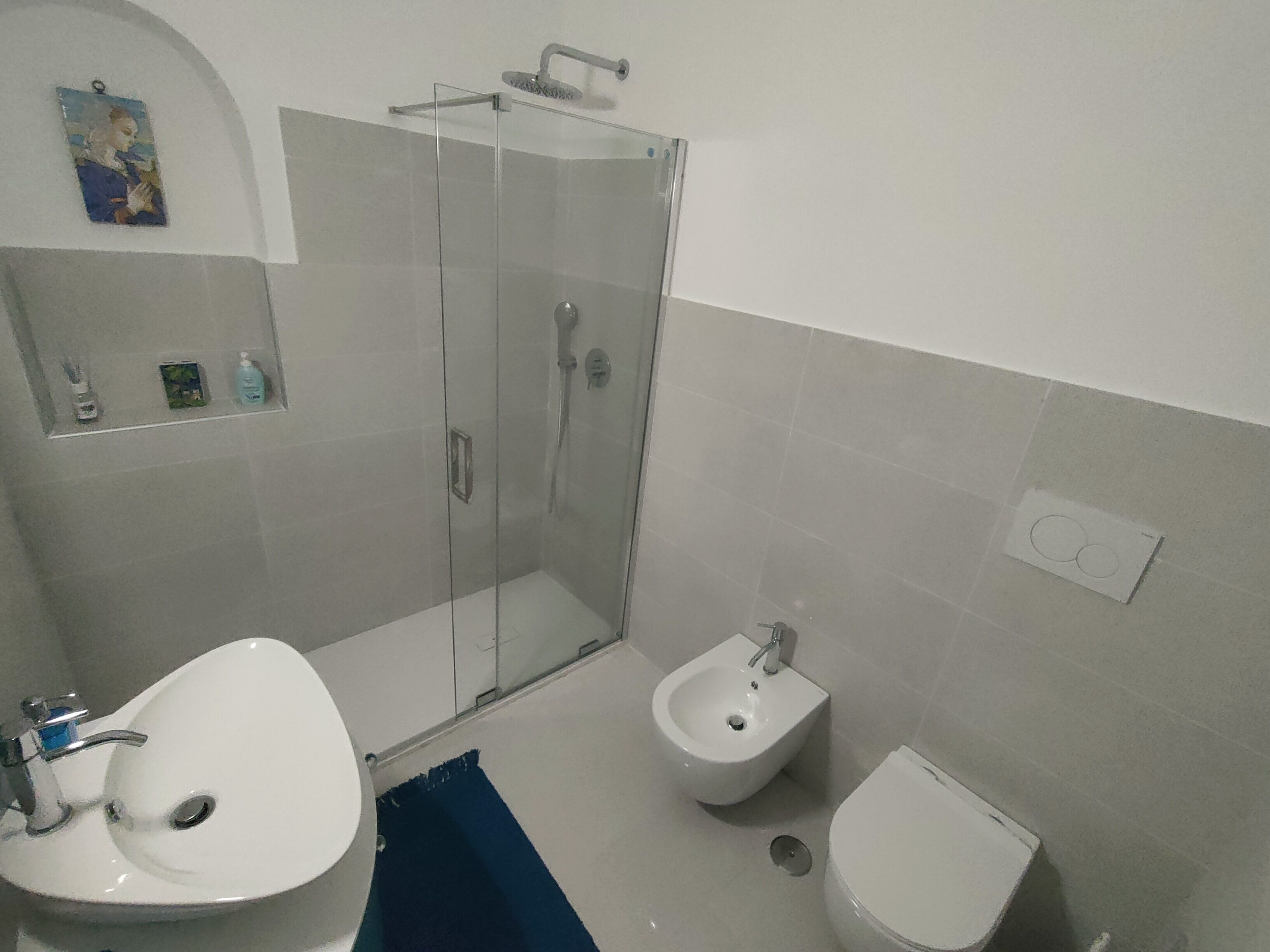 Une salle de bain avec une douche à parois de verre, un lavabo, un bidet et des toilettes.