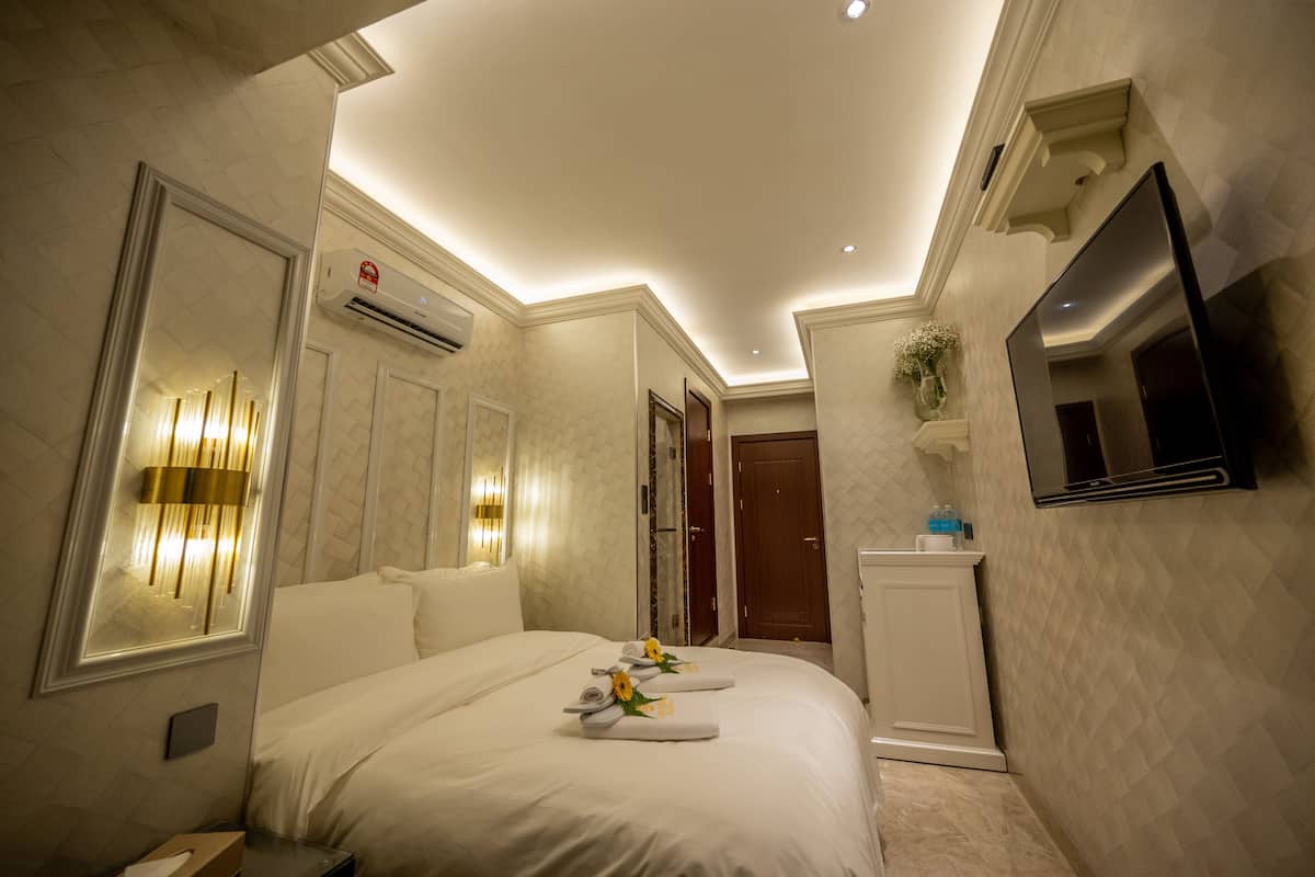 A hotel room with a bed, bedside lamps, a TV, and a mirror.