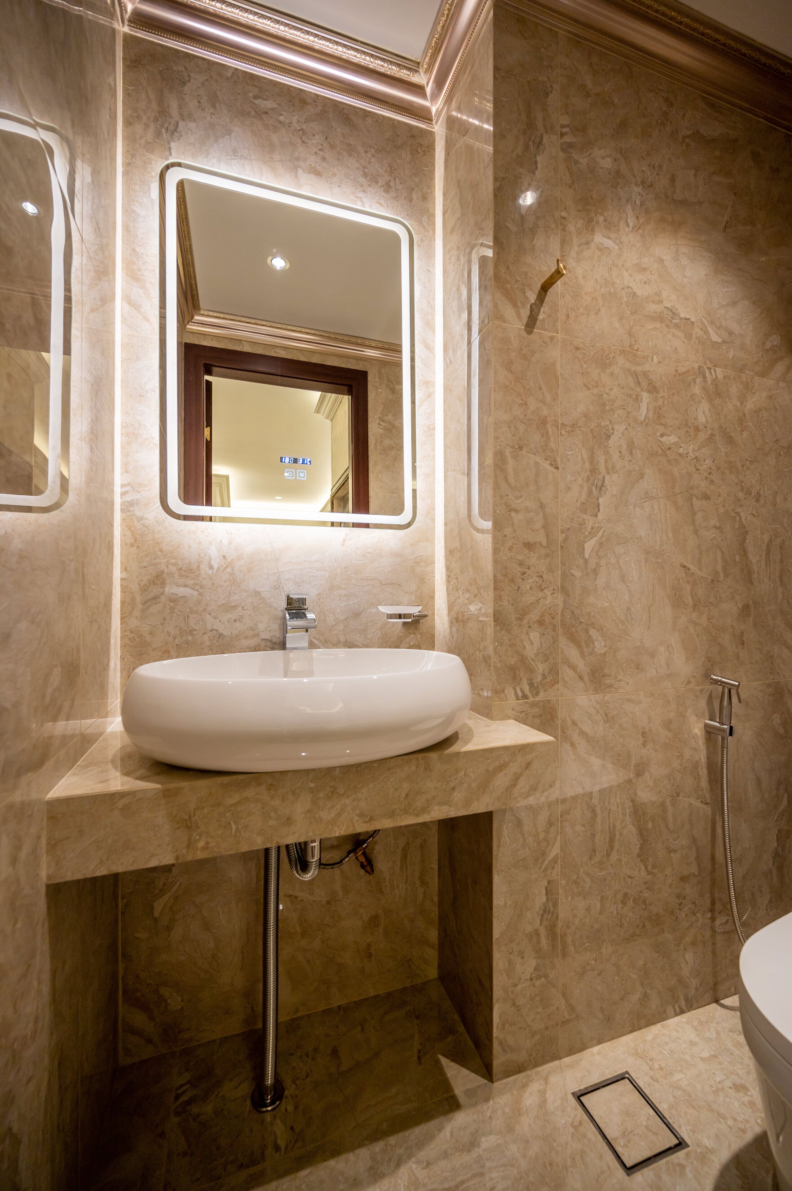 Un baño moderno con un lavamanos ovalado grande, un espejo con marco de madera y una zona de ducha.