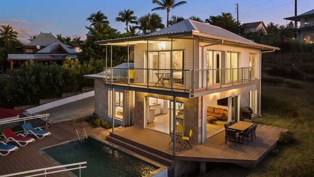 Una casa de dos pisos con balcón, piscina y terraza.