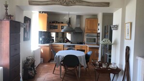 Cuina compacta amb armaris de fusta, una illa central i menjador amb taula i cadires.
