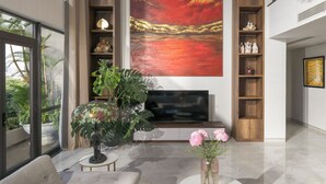 A modern living room with a large painting, a sofa, a coffee table, and a TV. - Tashi Oasis Hotel & Apartment (Da Nang)