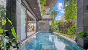 A modern indoor swimming pool with a geometric tile pattern, surrounded by lush greenery and a glass wall. - Tashi Oasis Hotel & Apartment (Da Nang)