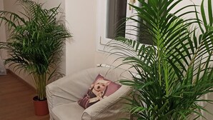 Una habitación con un sillón color beige, una mesita y dos plantas en macetas.